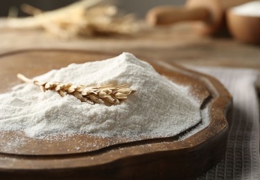 Photo of Wheat flour and spikelet on wooden table, closeup