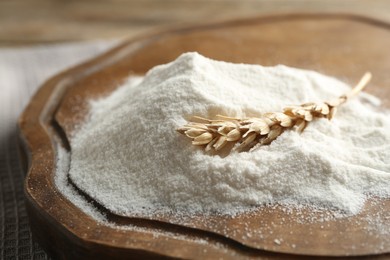 Photo of Wheat flour and spikelet on wooden table, closeup