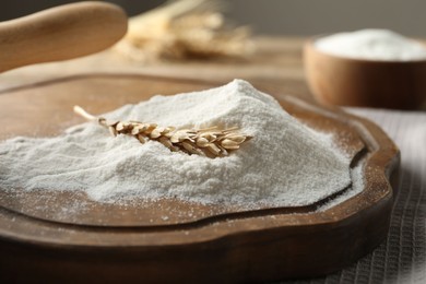 Photo of Wheat flour and spikelet on wooden table, closeup