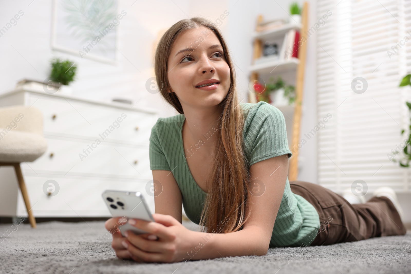 Photo of Teenage girl with smartphone on floor at home