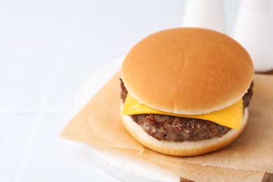 Photo of Tasty cheeseburger on white table, closeup. Space for text