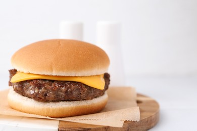 Photo of Tasty cheeseburger on white table, closeup. Space for text
