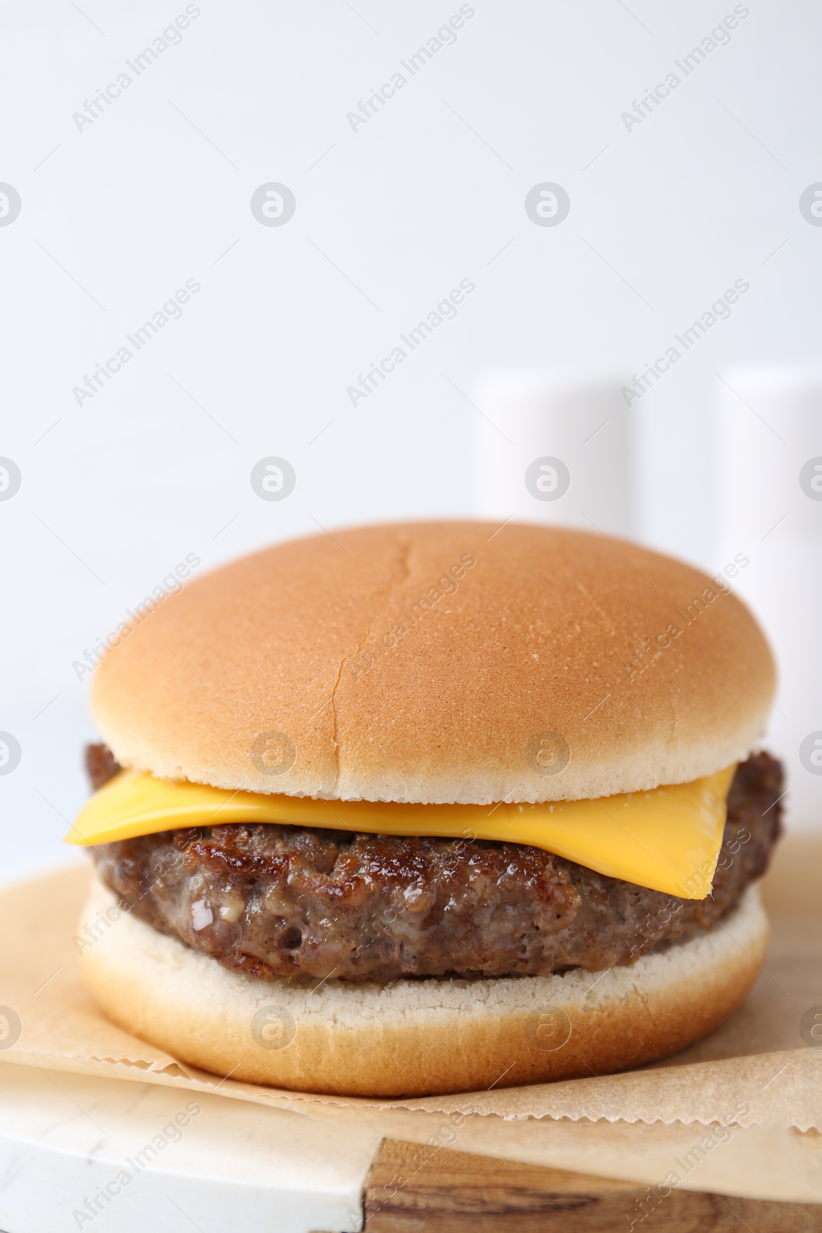 Tasty cheeseburger on white table, closeup. Space for text Photo of Tasty cheeseburger on white table, closeup. Space for text