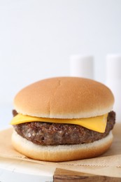 Photo of Tasty cheeseburger on white table, closeup. Space for text