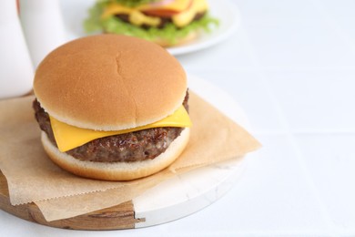 Photo of Tasty cheeseburger on white table, closeup. Space for text