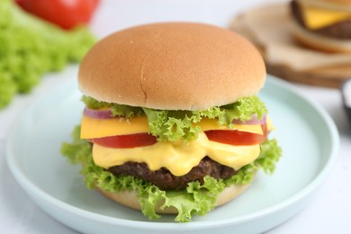 Photo of Tasty cheeseburger with lettuce and tomatoes on white table, closeup