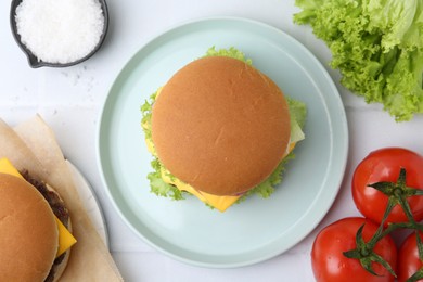 Photo of Tasty cheeseburger and ingredients on white table, flat lay