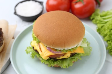 Photo of Tasty cheeseburger with lettuce and tomatoes on white table, closeup