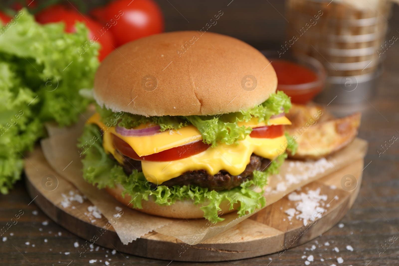 Tasty cheeseburger with potato wedges on wooden table, closeup Photo of Tasty cheeseburger with potato wedges on wooden table, closeup