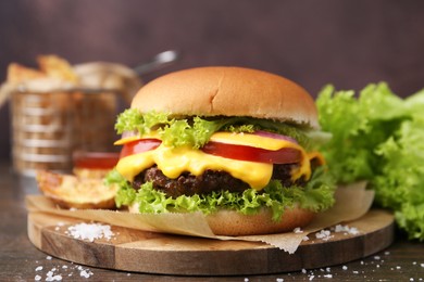 Photo of Tasty cheeseburger with potato wedges on wooden table, closeup