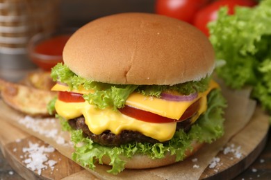 Photo of Tasty cheeseburger with potato wedges on wooden table, closeup