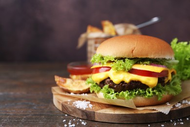 Photo of Tasty cheeseburger with potato wedges on wooden table, closeup. Space for text