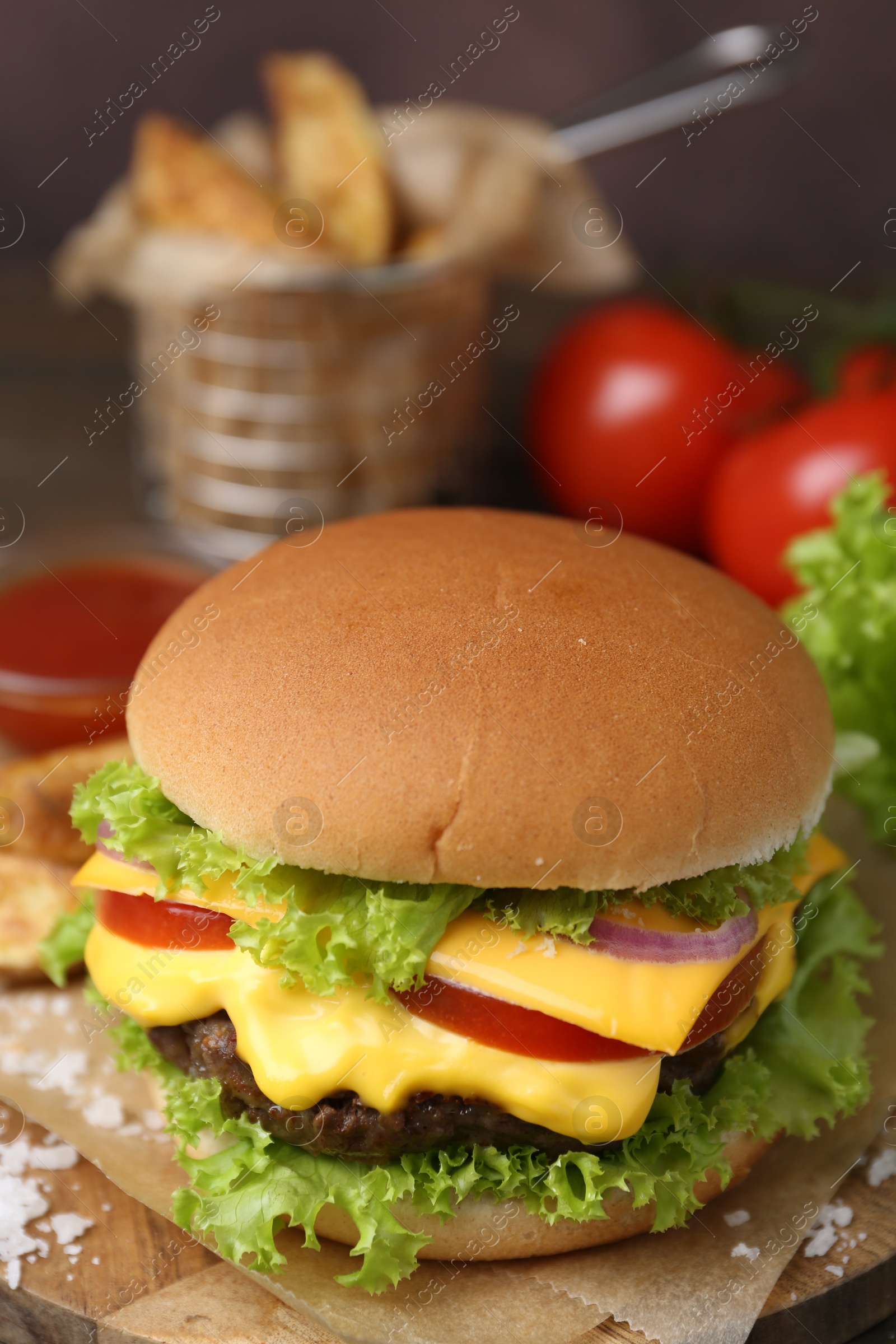 Tasty cheeseburger with lettuce and tomatoes on wooden table, closeup Photo of Tasty cheeseburger with lettuce and tomatoes on wooden table, closeup