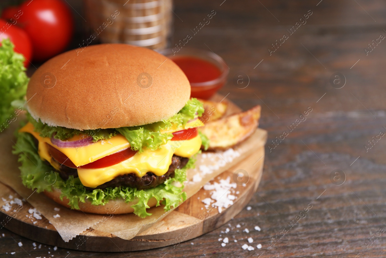 Tasty cheeseburger with potato wedges on wooden table, closeup. Space for text Photo of Tasty cheeseburger with potato wedges on wooden table, closeup. Space for text
