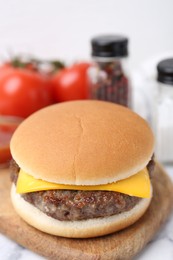 Photo of Tasty cheeseburger on white marble table, closeup