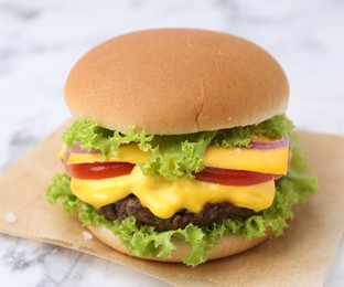 Photo of Tasty cheeseburger on white marble table, closeup