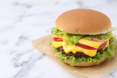 Photo of Tasty cheeseburger on white marble table, closeup. Space for text