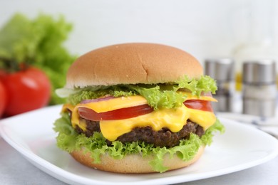 Photo of Tasty cheeseburger with lettuce and tomatoes on white table, closeup