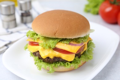 Photo of Tasty cheeseburger with lettuce and tomatoes on white table, closeup