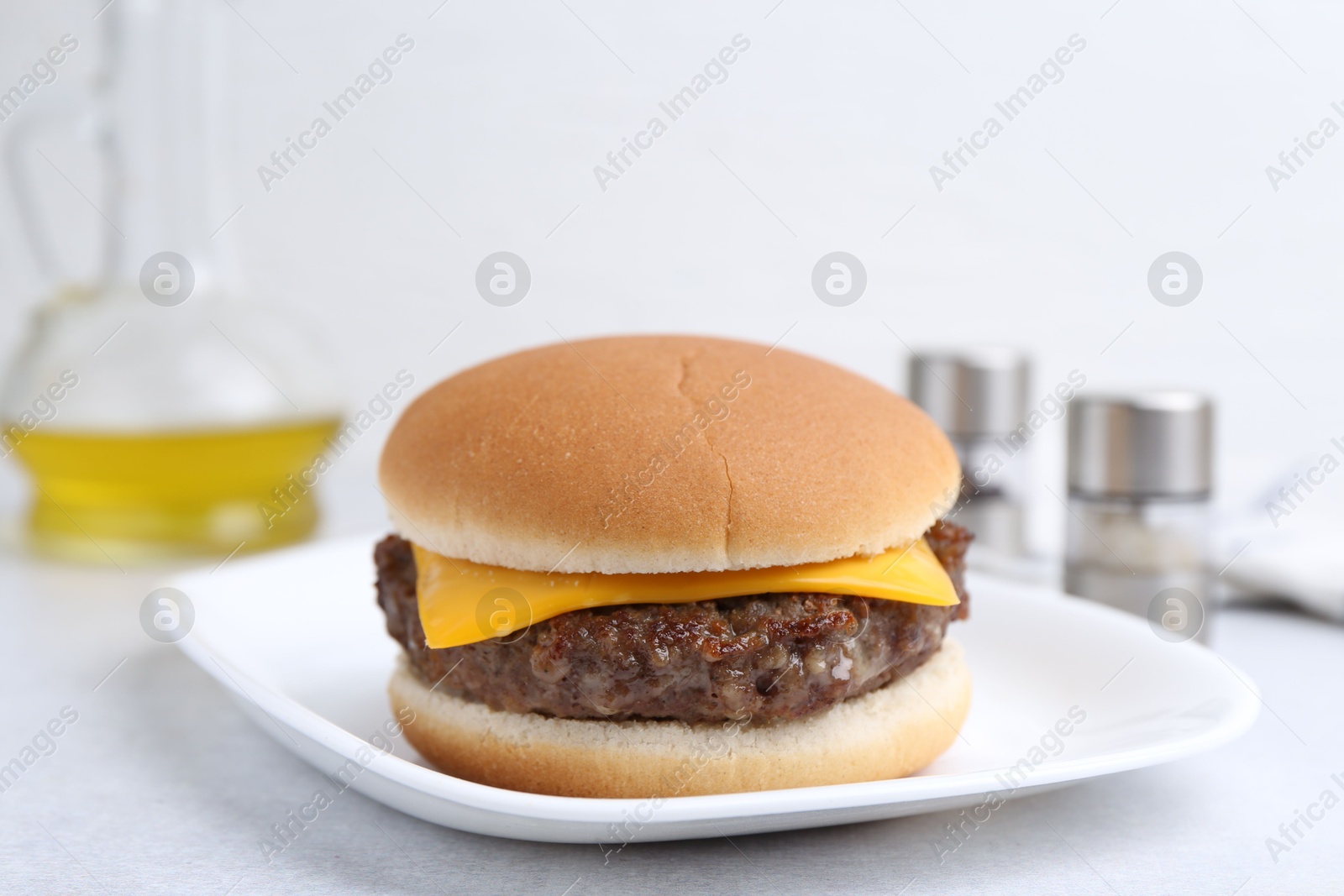 Photo of Cheeseburger with tasty patty on white table, closeup