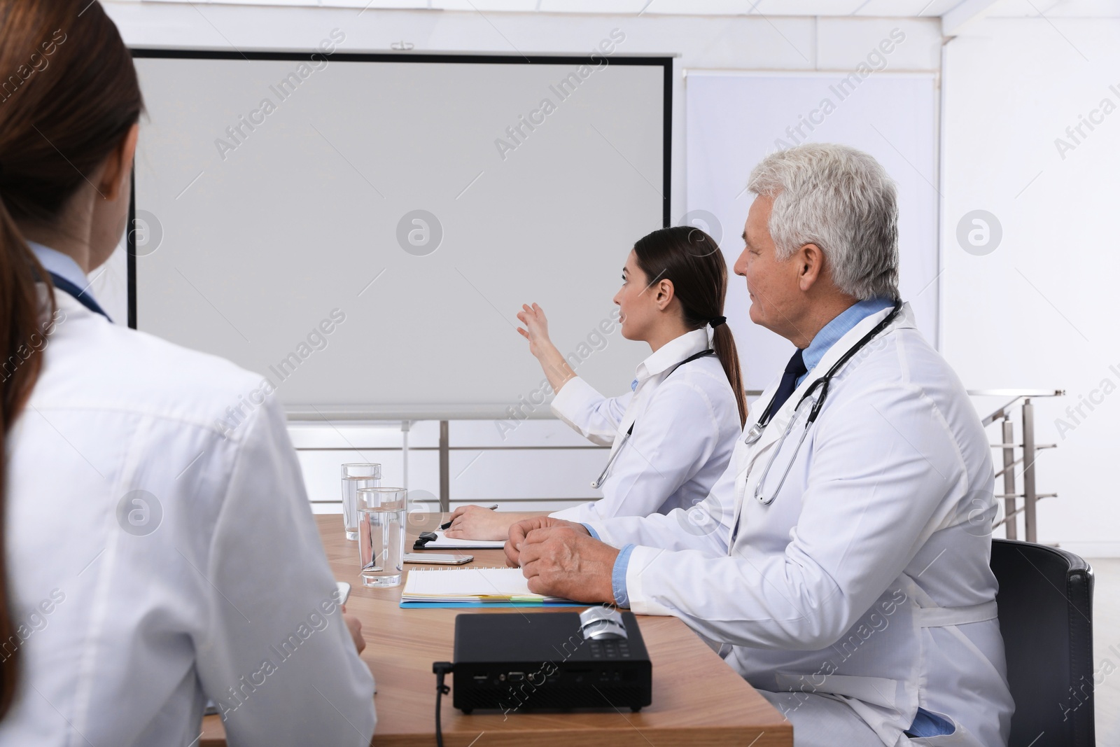 Team of doctors using video projector during conference indoors Photo of Team of doctors using video projector during conference indoors