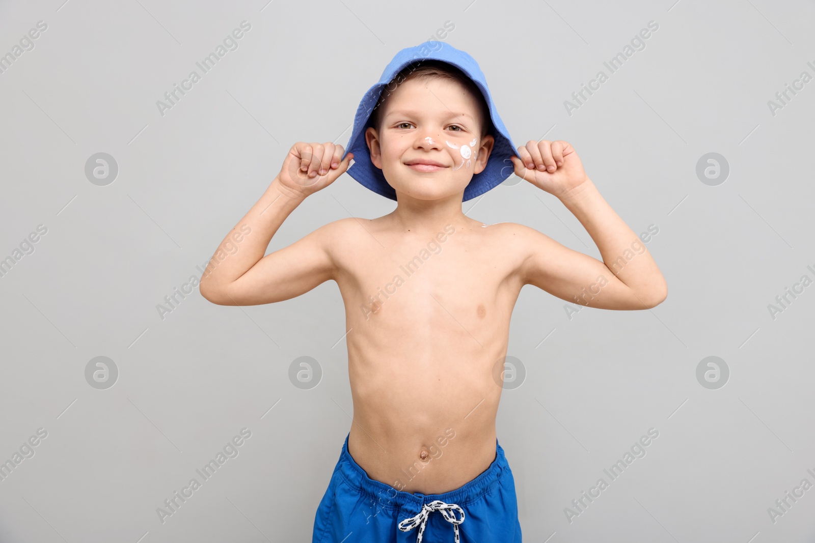 Photo of Little boy with sun protection cream on his skin against light grey background