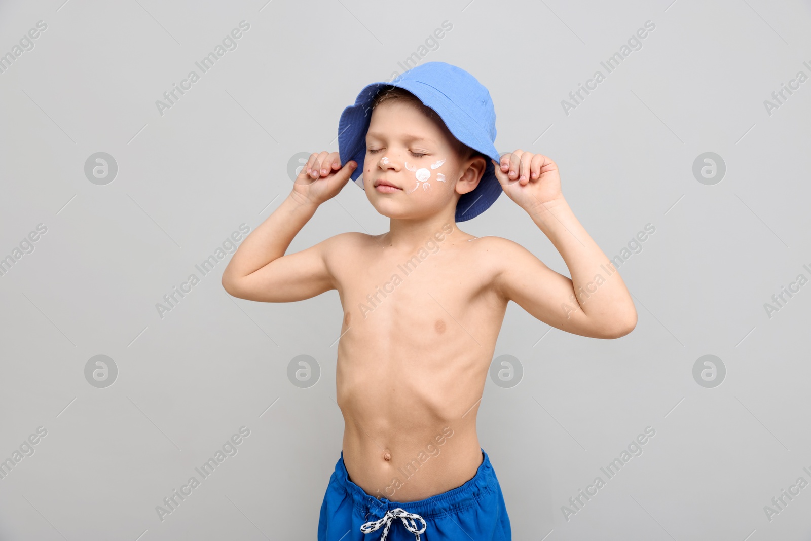 Little boy with sun protection cream on his skin against light grey background Photo of Little boy with sun protection cream on his skin against light grey background