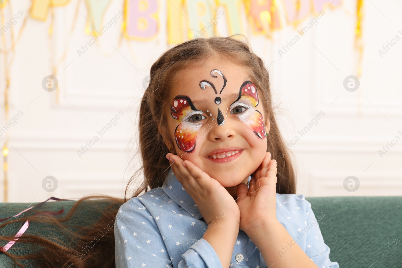 Photo of Cute girl with butterfly face painting indoors