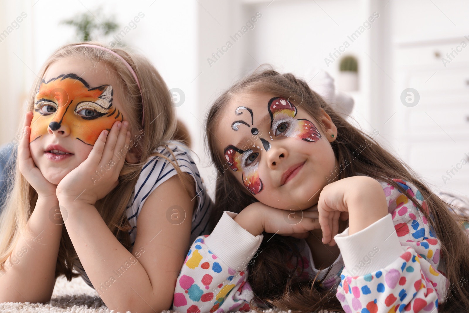 Photo of Cute girls with colorful face paintings indoors