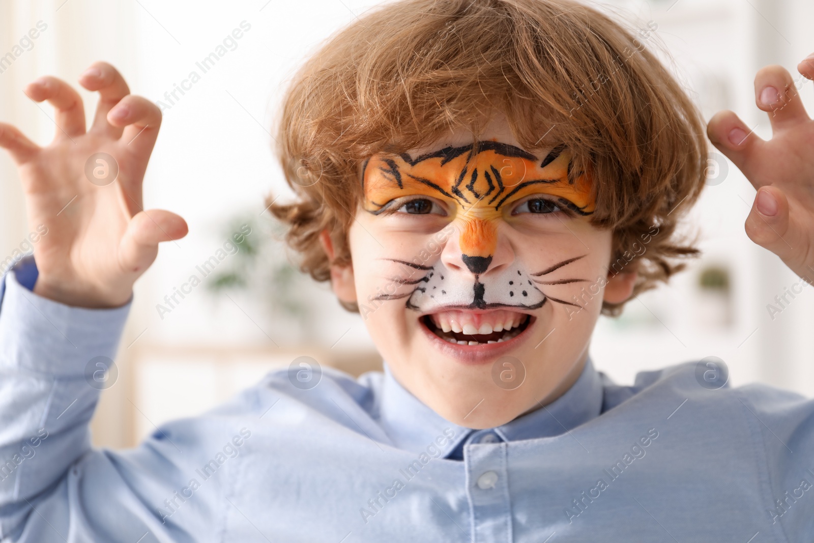 Cute boy with tiger face painting indoors Photo of Cute boy with tiger face painting indoors