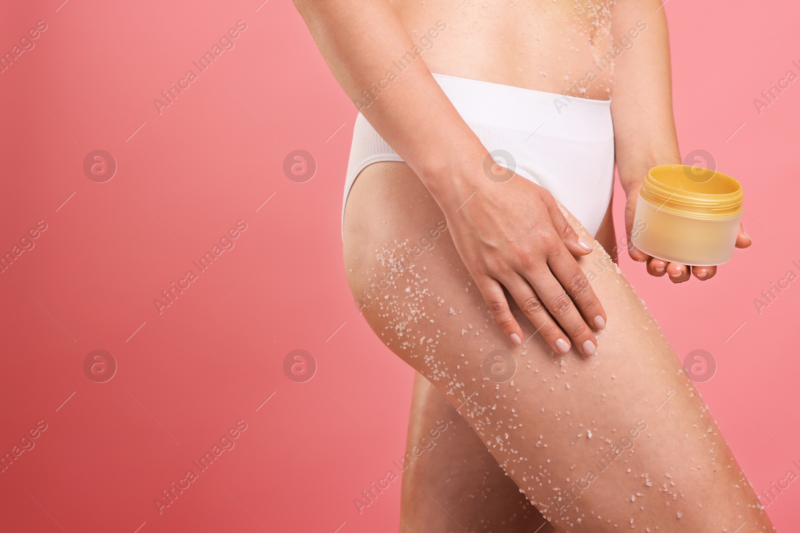 Woman with body scrub on her skin and jar against pink background, closeup. Space for text Photo of Woman with body scrub on her skin and jar against pink background, closeup. Space for text