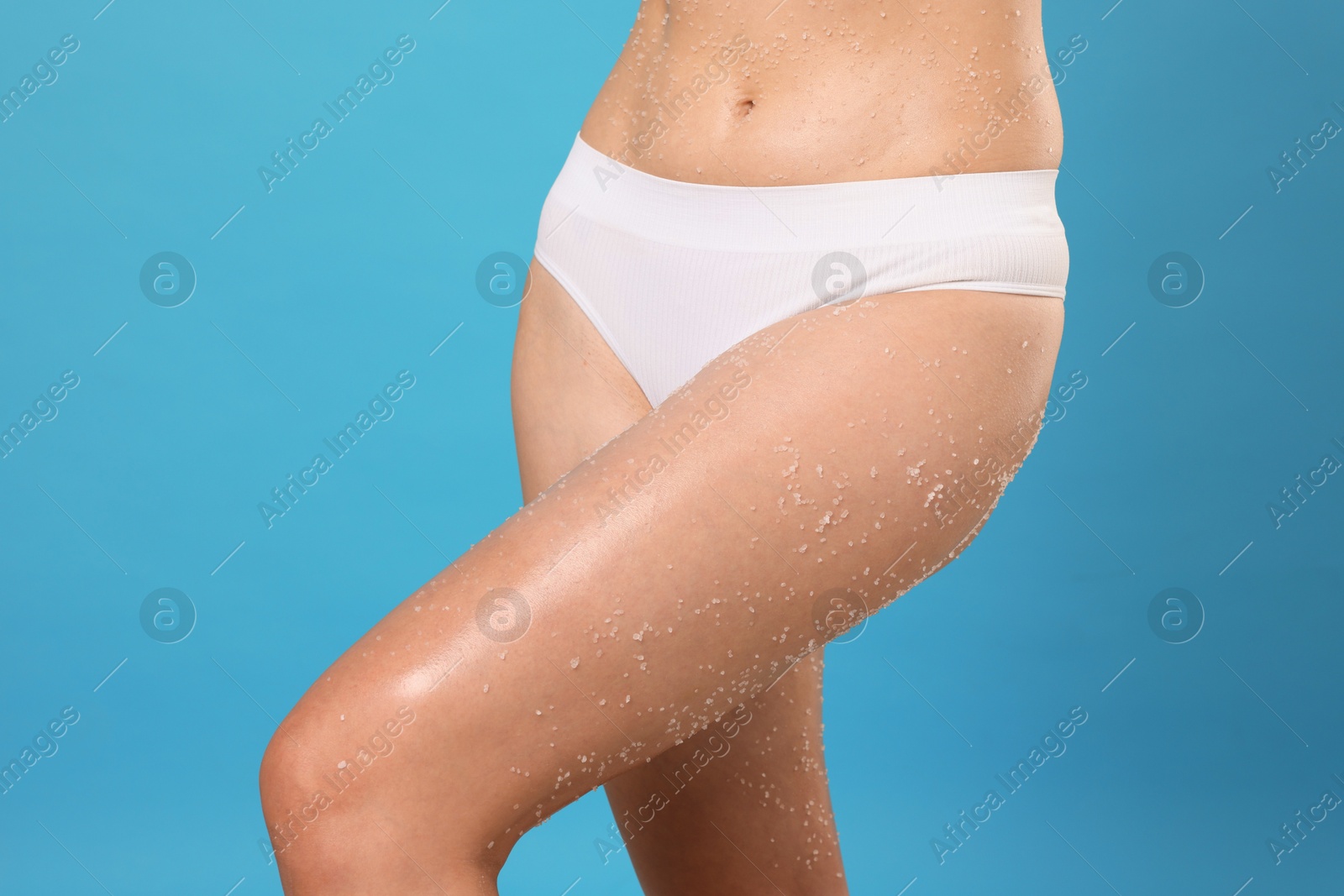 Woman with body scrub on her skin against light blue background, closeup Photo of Woman with body scrub on her skin against light blue background, closeup
