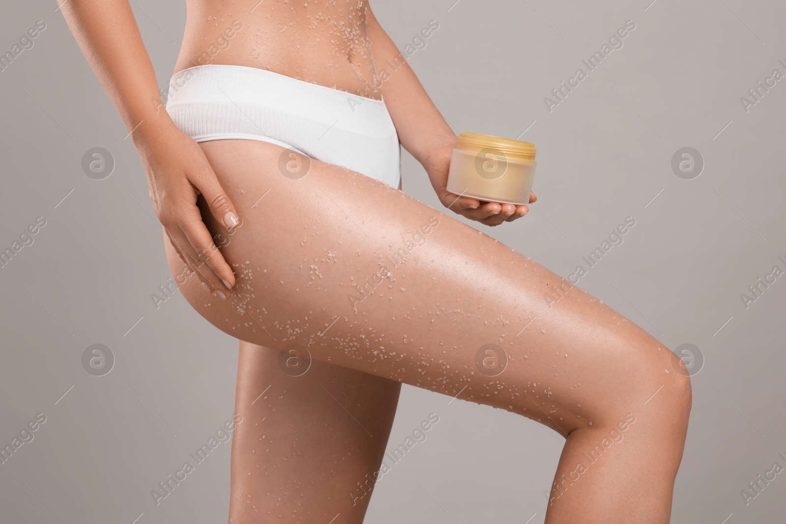 Woman with body scrub on her skin and jar against grey background, closeup Photo of Woman with body scrub on her skin and jar against grey background, closeup