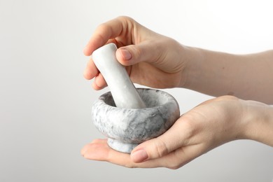 Photo of Woman with mortar and pestle on light background, closeup