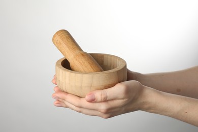 Photo of Woman with mortar and pestle on light background, closeup