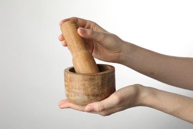 Photo of Woman with mortar and pestle on light background, closeup. Space for text