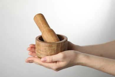 Photo of Woman with mortar and pestle on light background, closeup