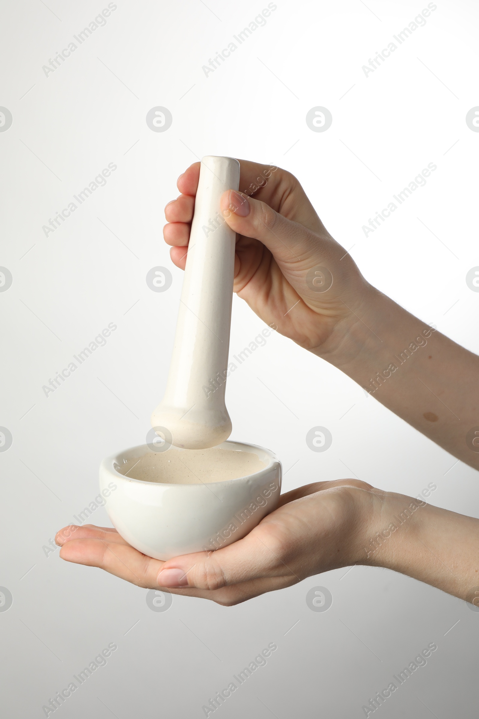 Woman with mortar and pestle on light background, closeup Photo of Woman with mortar and pestle on light background, closeup
