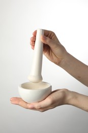Photo of Woman with mortar and pestle on light background, closeup