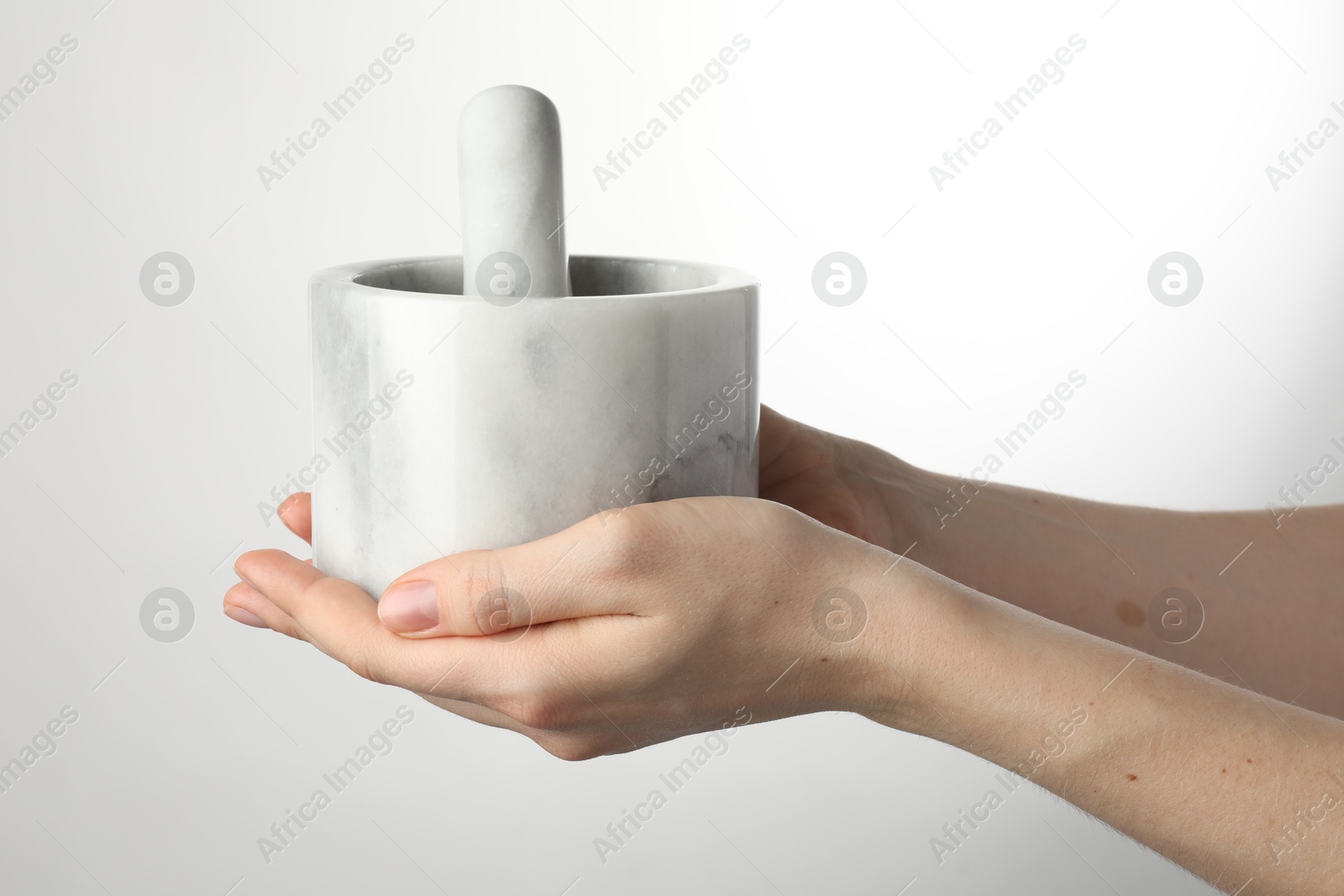 Woman with mortar and pestle on light background, closeup Photo of Woman with mortar and pestle on light background, closeup