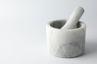 Photo of Marble mortar with pestle on white background, closeup. Space for text