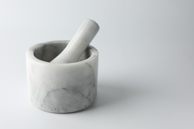 Photo of Marble mortar with pestle on white background, space for text