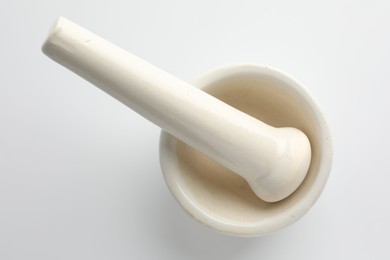 Photo of Ceramic mortar with pestle on white background, top view