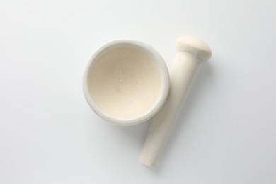 Photo of Ceramic mortar with pestle on white background, flat lay