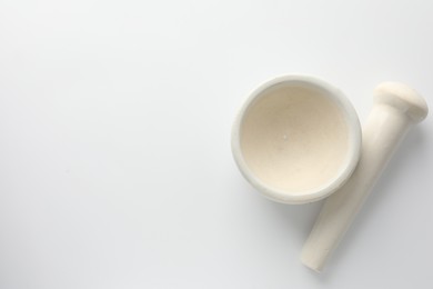 Photo of Ceramic mortar with pestle on white background, flat lay. Space for text