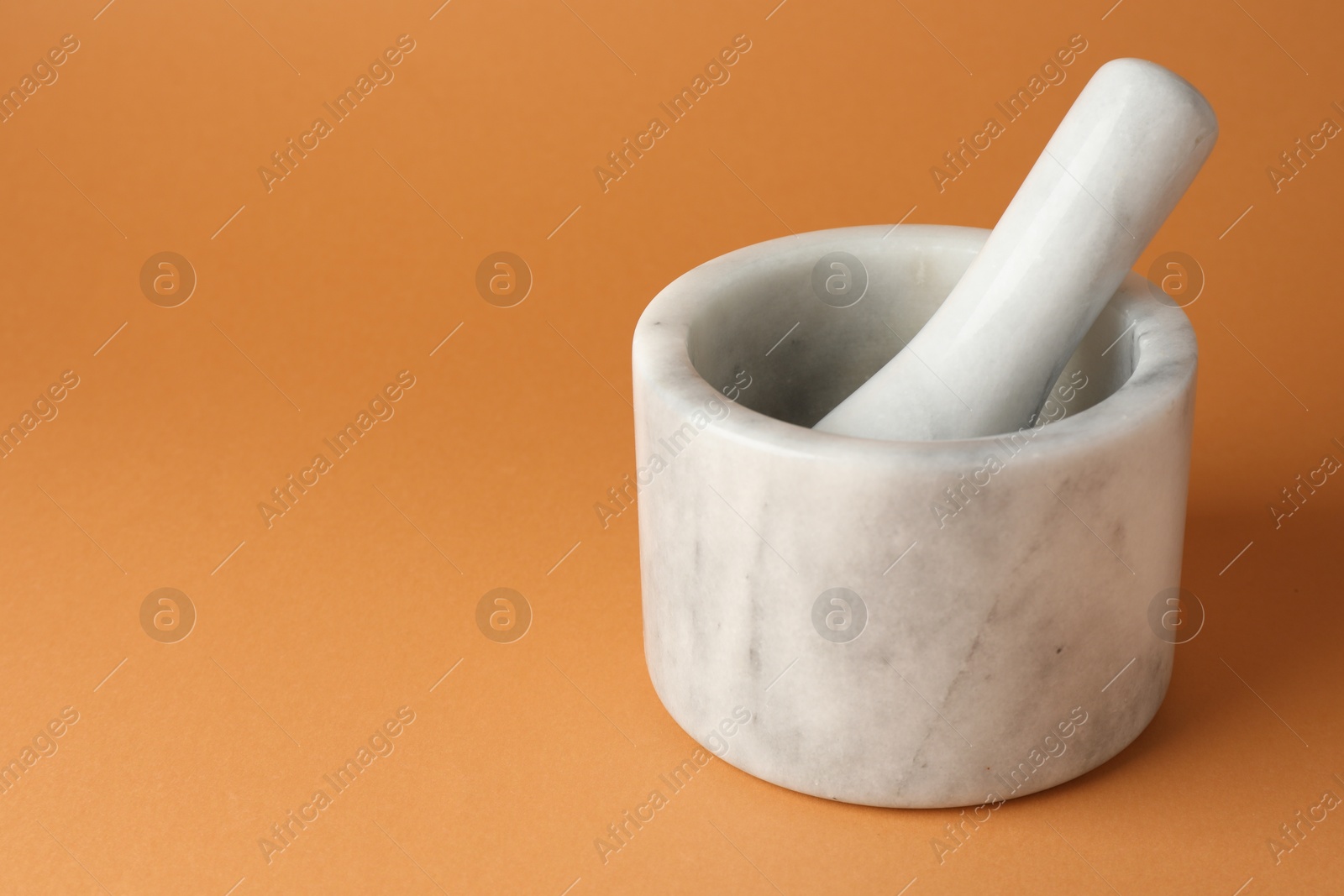 Marble mortar and pestle on light brown background, closeup. Space for text Photo of Marble mortar and pestle on light brown background, closeup. Space for text