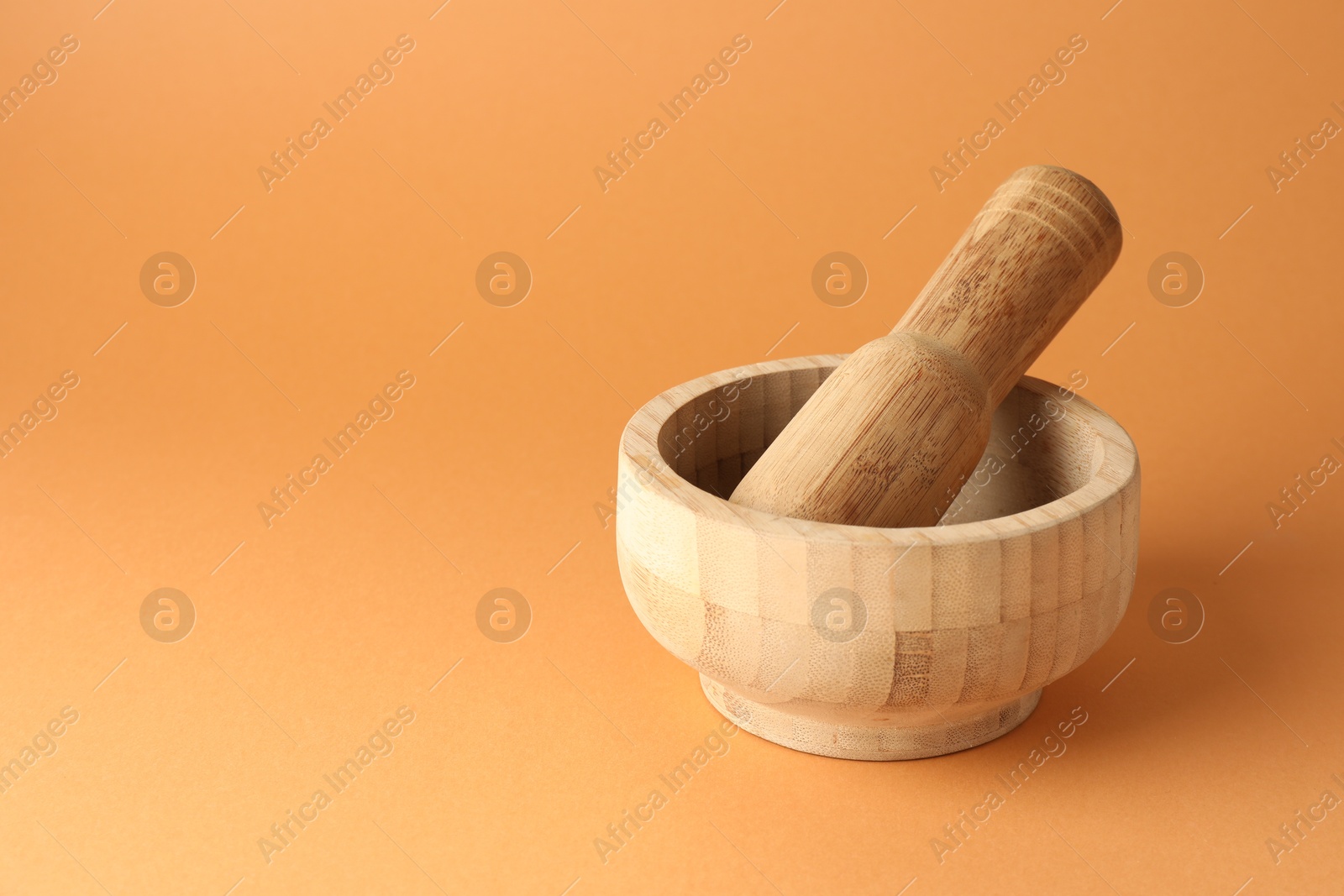 Wooden mortar and pestle on light brown background, closeup. Space for text Photo of Wooden mortar and pestle on light brown background, closeup. Space for text