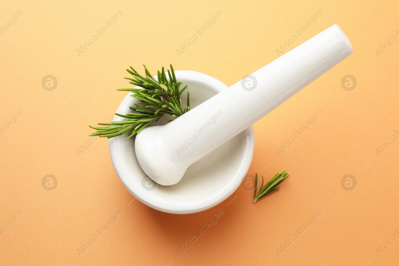 Ceramic mortar with rosemary and pestle on light brown background, top view Photo of Ceramic mortar with rosemary and pestle on light brown background, top view