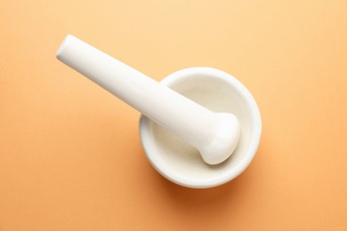 Photo of Ceramic mortar and pestle on light brown background, top view