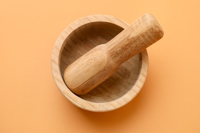 Photo of Wooden mortar and pestle on light brown background, top view